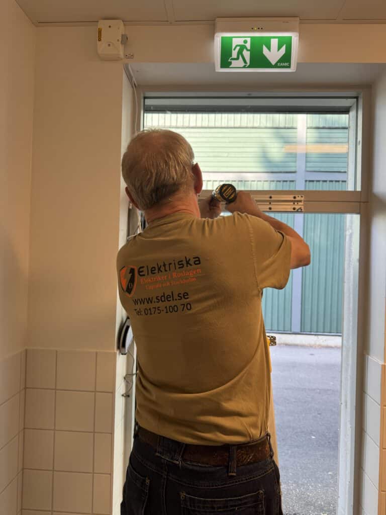Behörig elektriker från SD Elektriska AB installerar dörrautomatik för Täby kommun